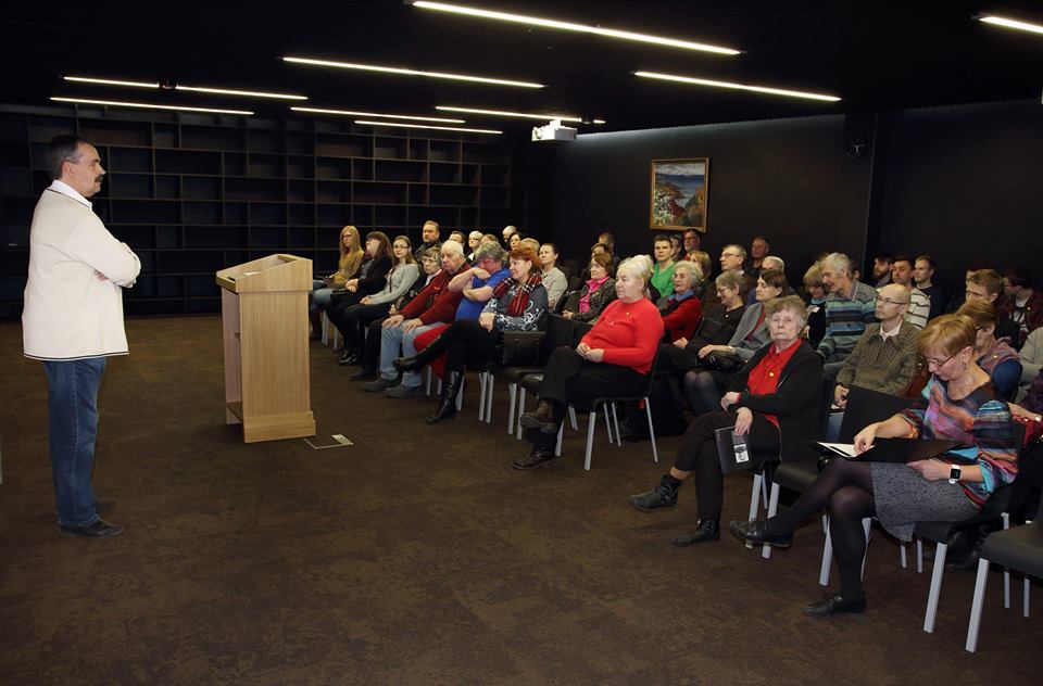 Esimene loeng. Esineja kõnepuldi kõrval. Rahvas istub toolidel.